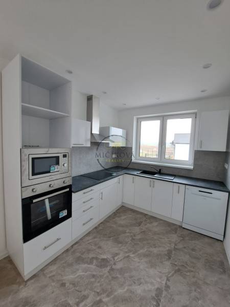 Küche in einem Einfamilienhaus mit weißen Schränken und eingebauten Geräten.