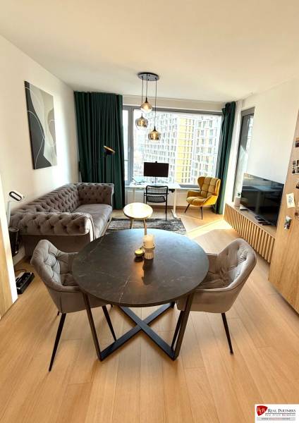 Wohnzimmer mit Sofa, Esstisch und Holzboden in einer Zweizimmerwohnung.