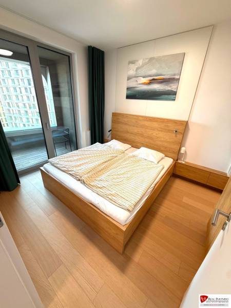 Schlafzimmer in einer 2-Zimmer-Wohnung mit Bett, Balkon und Boden in Holzoptik.
