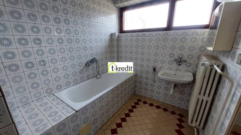 Badezimmer mit gemusterten Fliesen, Badewanne, Waschbecken und Heizkörper in einem Einfamilienhaus.