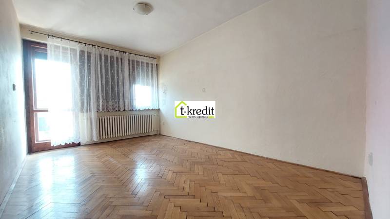 Ein Zimmer in einem Einfamilienhaus mit einem Holzboden und einem großen Fenster.