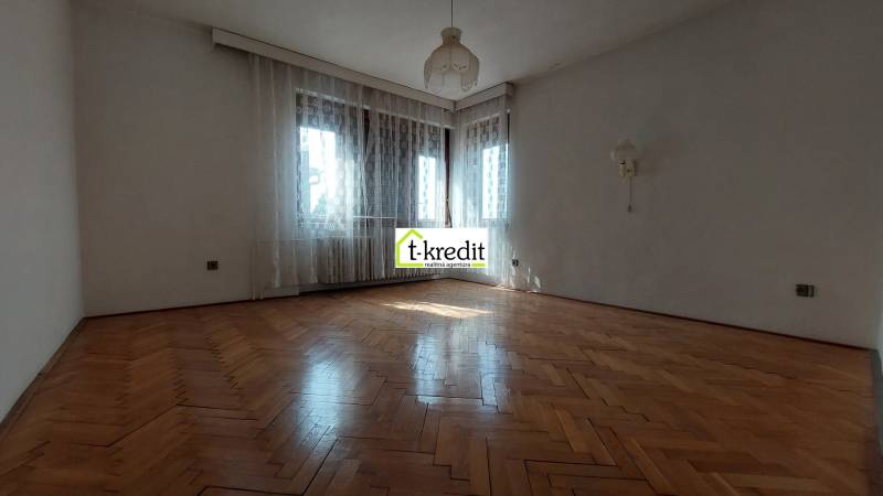 Ein geräumiges Zimmer mit Holzboden, weißen Wänden und Vorhängen in einem Einfamilienhaus.