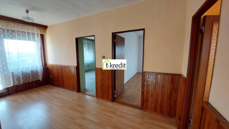 Ein Zimmer in einem Einfamilienhaus mit einem Boden in Holzoptik und einer Wandverkleidung aus Holz.