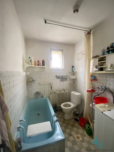 Badezimmer in einem Einfamilienhaus mit Badewanne, Waschmaschine und Fenster.