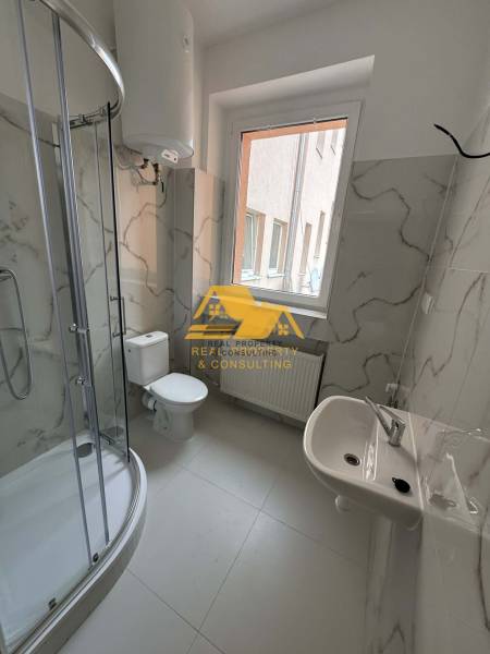 Badezimmer in einer Einzimmerwohnung mit einer Eckdusche und Keramikfliesen.