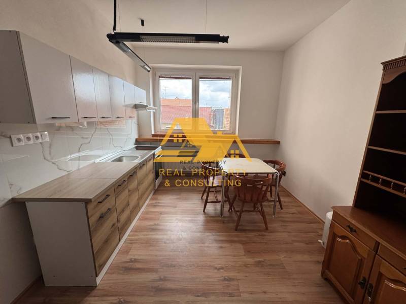 Küche in einer Einzimmerwohnung mit Tisch, Stühlen und Boden in Holzoptik.