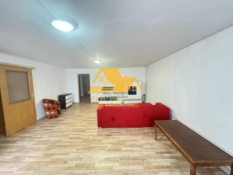 Wohnzimmer in einer Zweizimmerwohnung mit Holzboden und rotem Sofa.