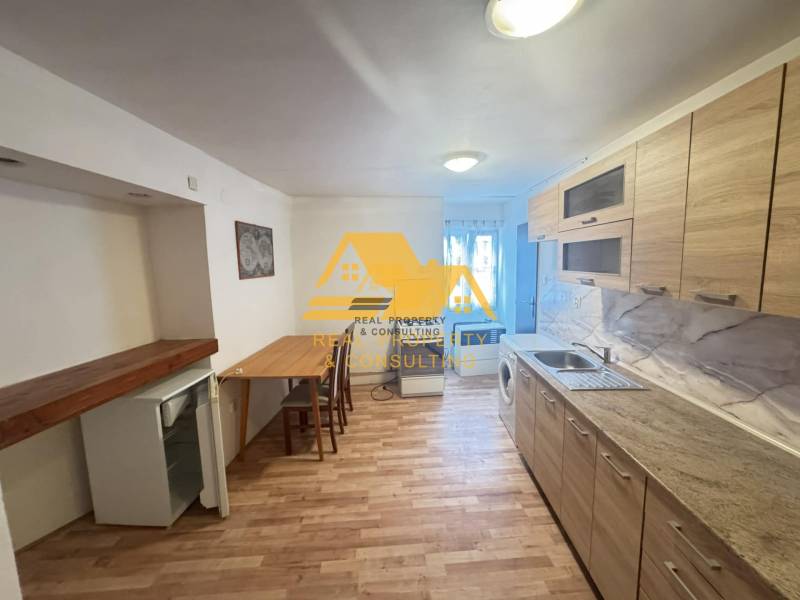 Küche in einer 2-Zimmer-Wohnung mit Holzdekorboden und hellem Mobiliar.