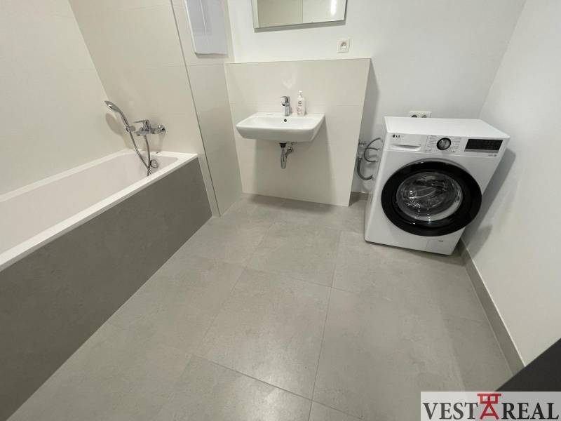Badezimmer mit Badewanne, Waschmaschine und Waschbecken in einer 2-Zimmer-Wohnung in der Novomestská Straße.