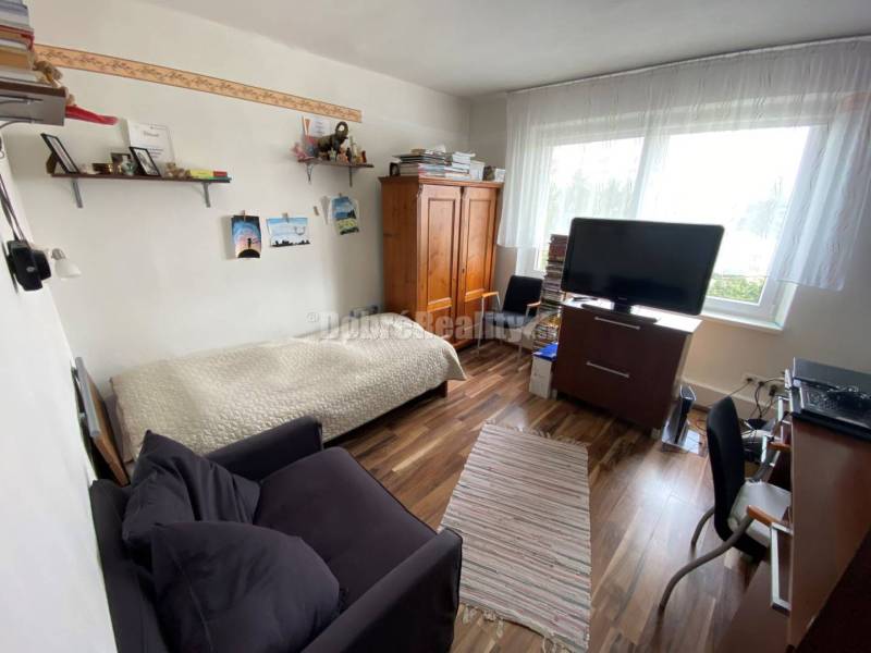 Wohnzimmer in einer 4-Zimmer-Wohnung mit Holzboden und Fernseher.