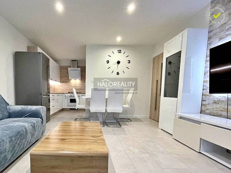 Wohnzimmer in einer 2-Zimmer-Wohnung mit stilvollen Möbeln und einer großen Wanduhr.