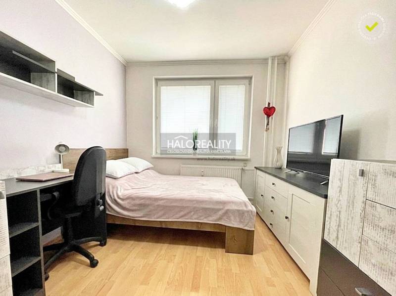 Schlafzimmer in einer 2-Zimmer-Wohnung mit Bett, Schreibtisch und Fernseher. Boden mit Holzdekor.