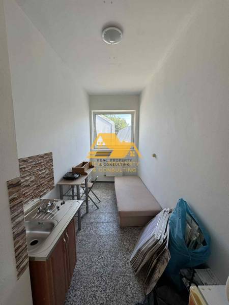 Kleine Garçonnière mit Waschbecken, Tisch und Liege, geeignet für praktisches Wohnen.