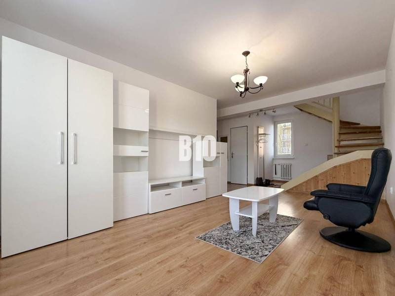 Wohnzimmer in einer Ferienwohnung mit weißen Möbeln und einem Boden in Holzoptik.