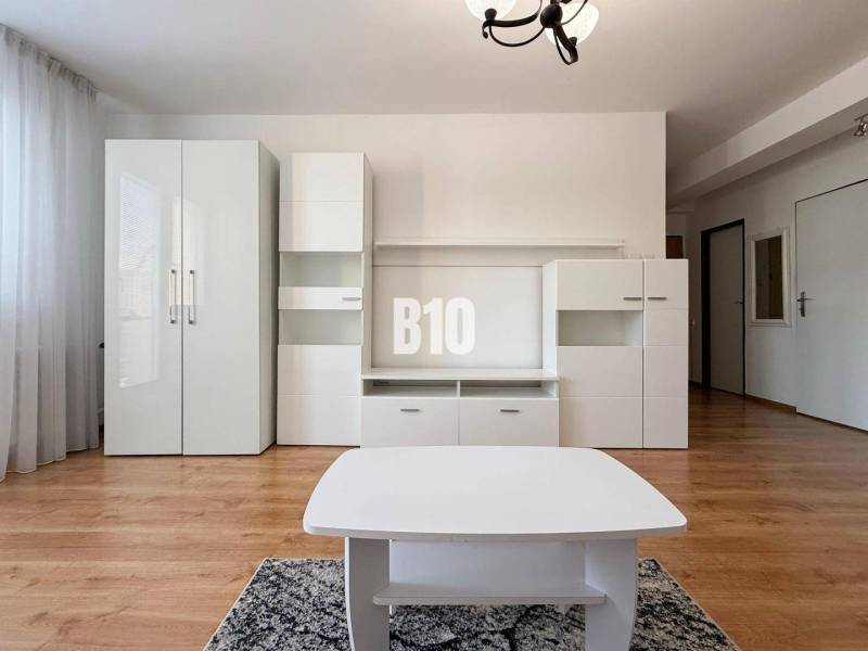 Innenraum einer Ferienwohnung mit weißen Möbeln und Boden in Holzoptik.