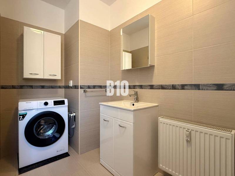 Badezimmer mit Waschmaschine, Waschbecken und Schränken im Ferienapartment.