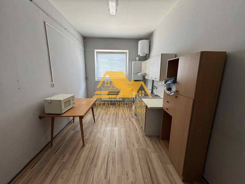 Einfache Einrichtung eines Einzimmerapartments mit Küchenzeile und Holzboden.