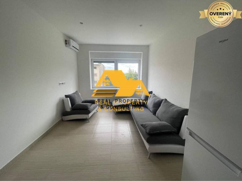 Wohnzimmer in einer 3-Zimmer-Wohnung mit zwei grauen Sofas und einem weißen Kühlschrank.
