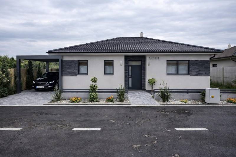 Ein Einfamilienhaus in Urmince mit eleganter Fassade und einem Parkplatz.