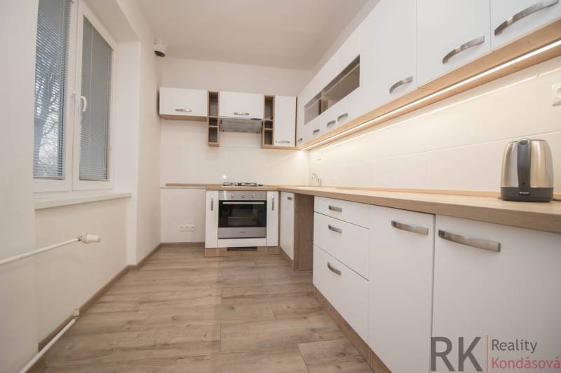 Küche mit Geräten, weißen Schränken und Holzboden in einer 2-Zimmer-Wohnung.