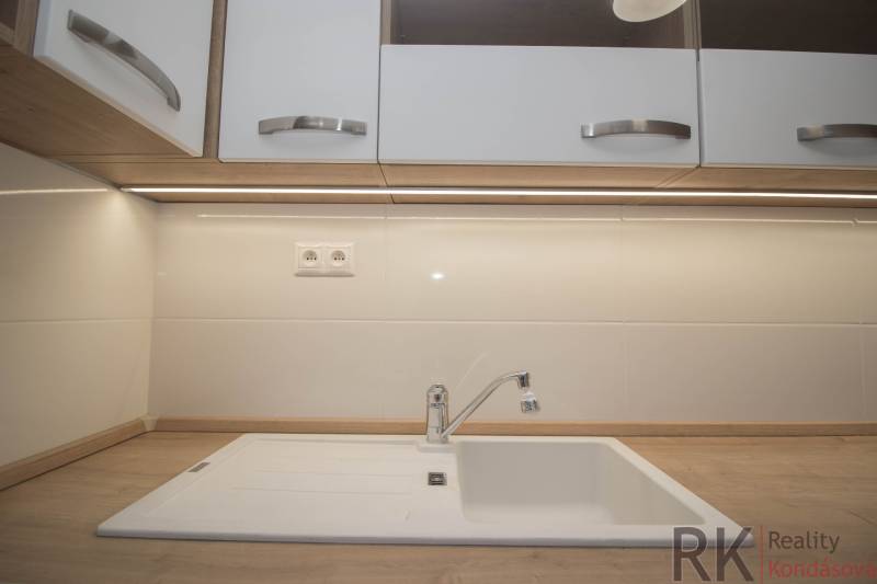 Küchenarbeitsplatte mit Holzdekor und weißem Spülbecken in einer 2-Zimmer-Wohnung.