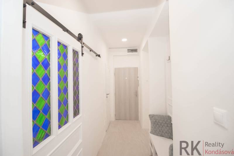 Flur mit Buntglastüren, Kleiderhaken und Holzelementen in einer 2-Zimmer-Wohnung.