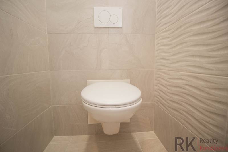 Badezimmer in einer 2-Zimmer-Wohnung mit weißer Toilette und hellen Fliesen.