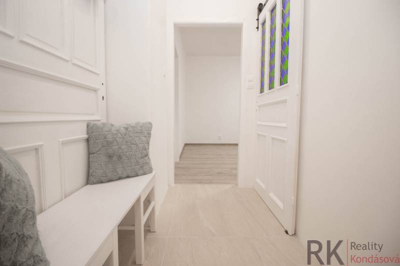 Ein heller Flur mit weißen Möbeln und dekorativen Kissen in einer 2-Zimmer-Wohnung.