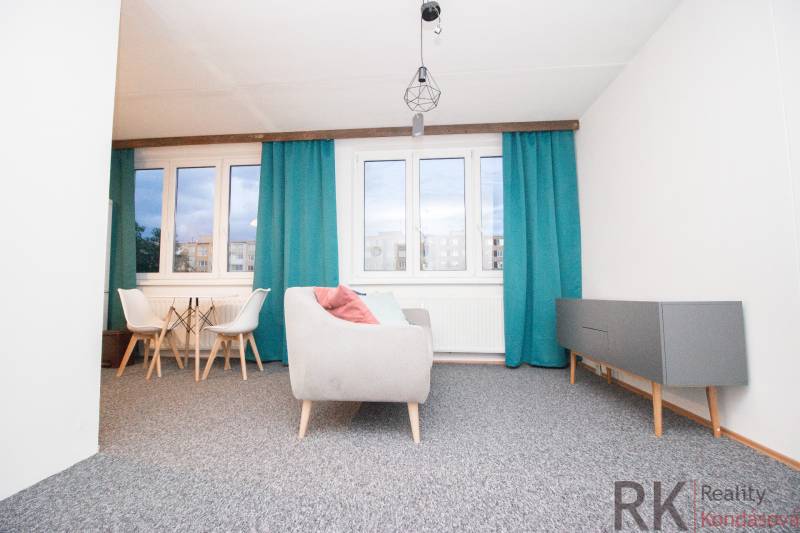 Wohnzimmer in einer 4-Zimmer-Wohnung mit blauen Vorhängen und grauen Möbeln.