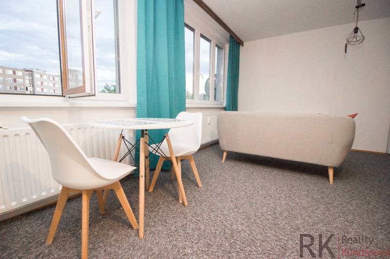 Wohnzimmer mit Tisch und Stühlen in einer 4-Zimmer-Wohnung, leuchtende Vorhänge, heller Teppich.