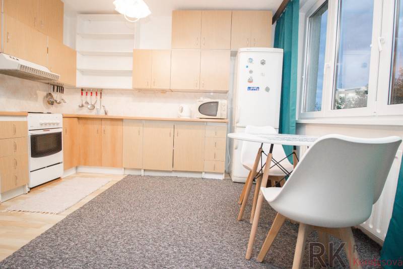 Küche mit weißen Möbeln und Esstisch in einer 4-Zimmer-Wohnung.