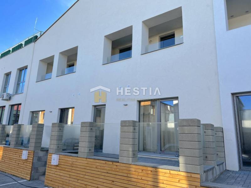 Neubau mit mehreren Balkonen und einer 2-Zimmer-Wohnung, Betonzaun und Terrasse.