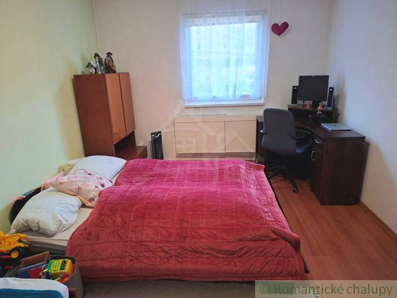 Ein Schlafzimmer in einem Einfamilienhaus mit Bett, Schreibtisch und einem Boden in Holzoptik.