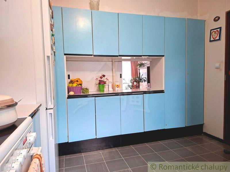 Eine Küche in einem Einfamilienhaus mit blauen Schränken und weißen Geräten.