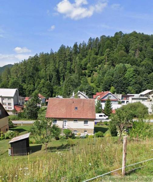 Ein Einfamilienhaus in Liptovské Revúce, umgeben von Grünflächen und weiteren Häusern vor dem Hintergrund eines Waldes.