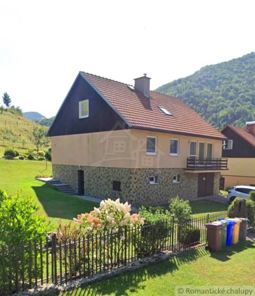 Ein Einfamilienhaus in Liptovské Revúce mit rotem Dach, Garten und einem Blumenzaun.