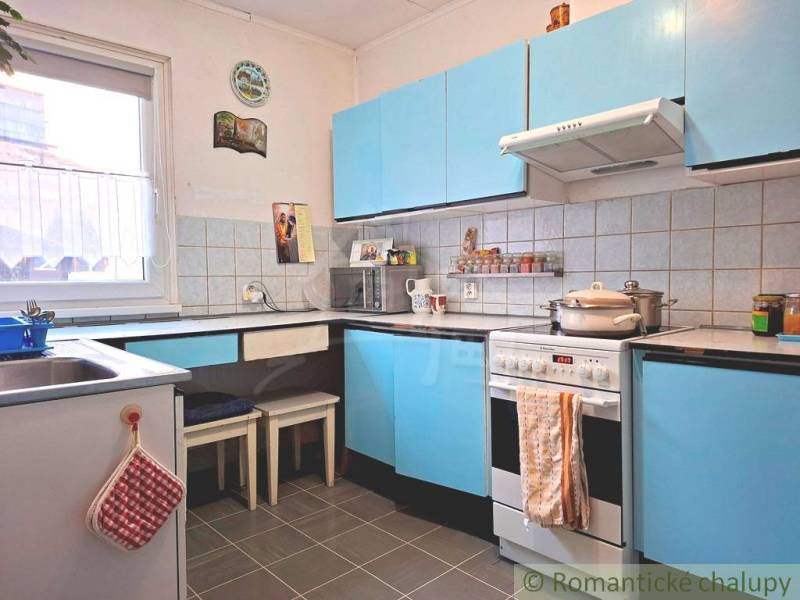 Küche in einem Einfamilienhaus mit blauen Schränken und einer gefliesten Wand.