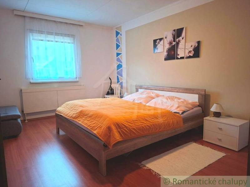 Ein Schlafzimmer in einem Einfamilienhaus mit Bett, Dekoration und einem Boden in Holzoptik.