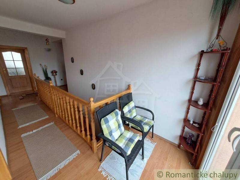 Innenraum eines Einfamilienhauses mit Treppe, Stühlen und Boden in Holzoptik.