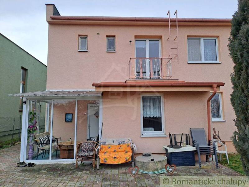 Ein Einfamilienhaus in Veľké Ripňany mit einer verglasten Terrasse und einem gepflasterten Hof.