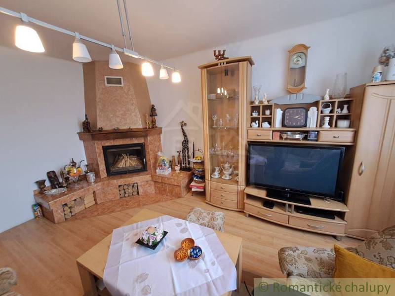 Wohnzimmer in einem Einfamilienhaus mit Kamin, Holzbodenoptik und Vitrine.