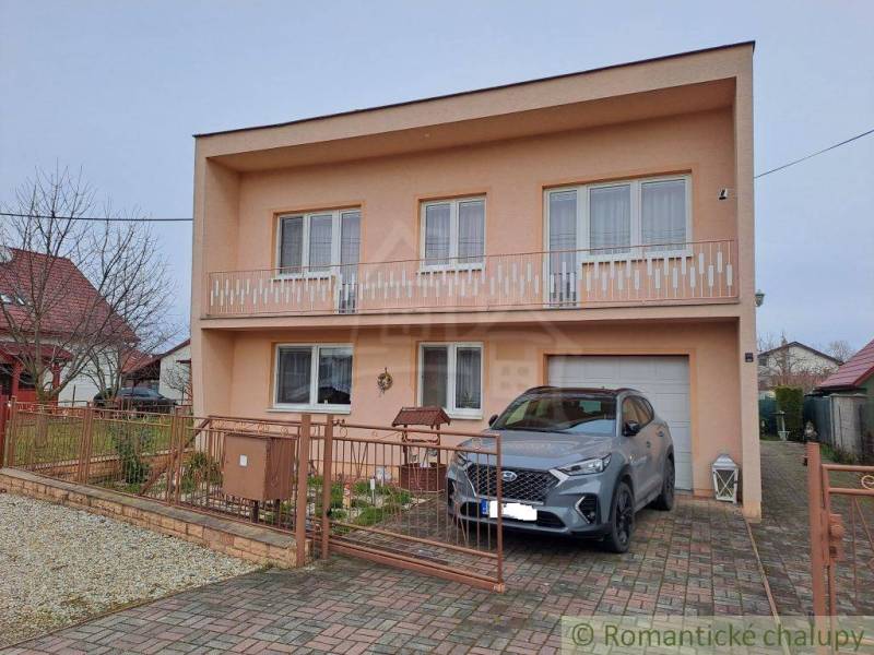 Ein Einfamilienhaus in Veľké Ripňany mit einem Balkon und einem Auto in der Einfahrt.