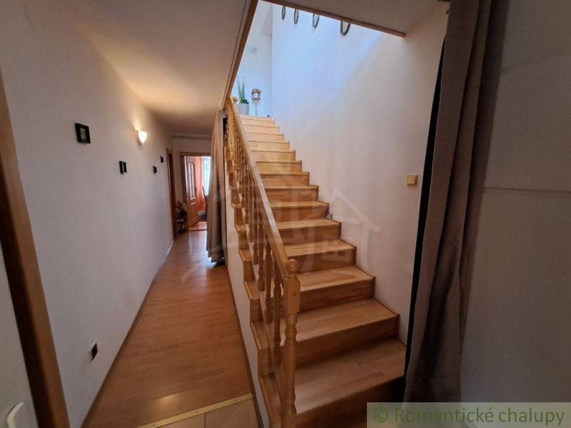 Der Flur eines Einfamilienhauses mit einer Holztreppe und einem Boden in Holzoptik.