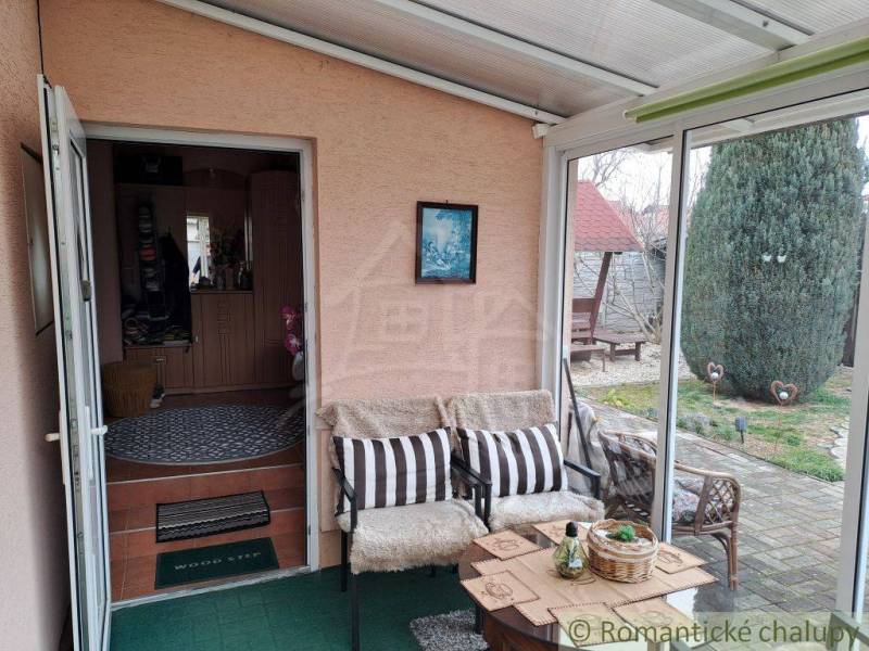 Ein Wintergarten im Einfamilienhaus mit bequemen Sitzgelegenheiten und Blick in den Garten.