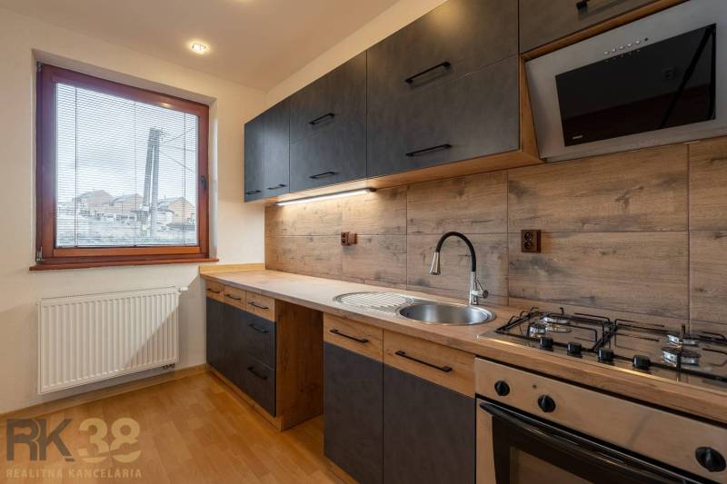 Küche in einer Wohnung mit 5 oder mehr Zimmern mit eleganter Küchenzeile und Bodenbelag in Holzoptik.
