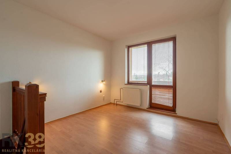 Ein Zimmer mit einem Boden in Holzoptik in einer Wohnung mit fünf oder mehr Zimmern, helle Wände, großes Fenster.