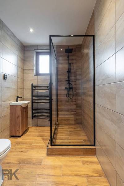 Badezimmer in einer Wohnung mit 5 oder mehr Zimmern mit Holzboden und Duschkabine.
