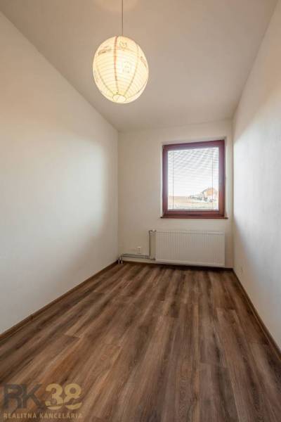 Zimmer in einer Wohnung mit 5 oder mehr Zimmern mit einem Boden in Holzoptik und einem Fenster.