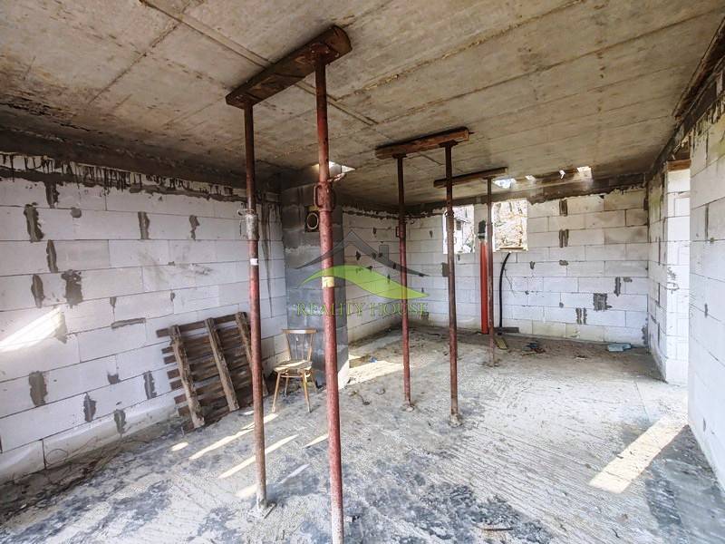 Das Innere der Hütte im Bau mit temporären Stützen, unverkleideten Ziegeln und Baumaterial.