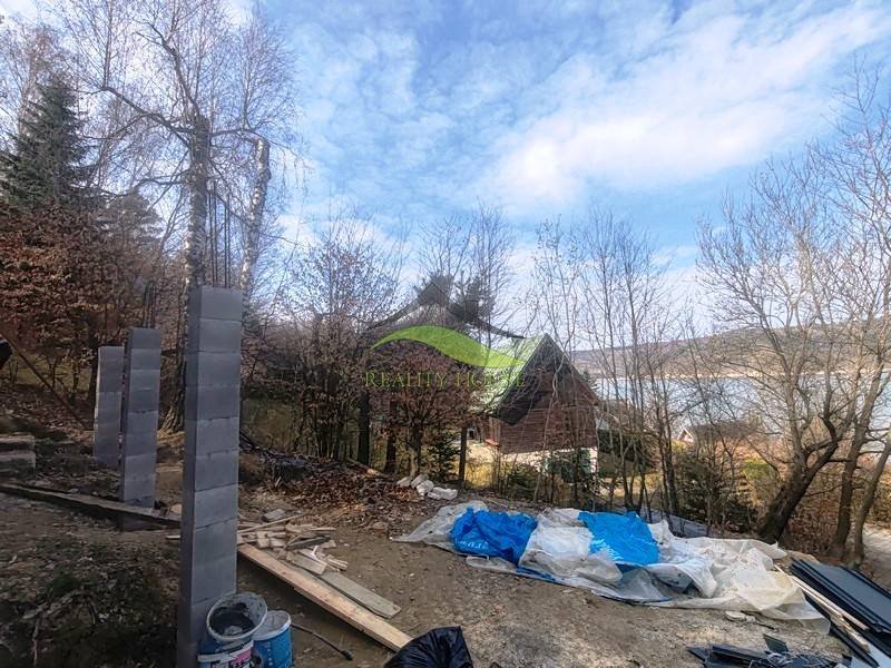 Baumaterial neben der Hütte auf Zajačia debra in Holčíkovce mit Blick auf die Wasserfläche.